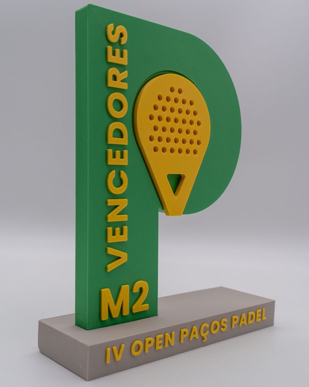 Troféu verde e amarelo em forma de P com raquete de padel, base cinzenta com a inscrição IV Open Paços Padel