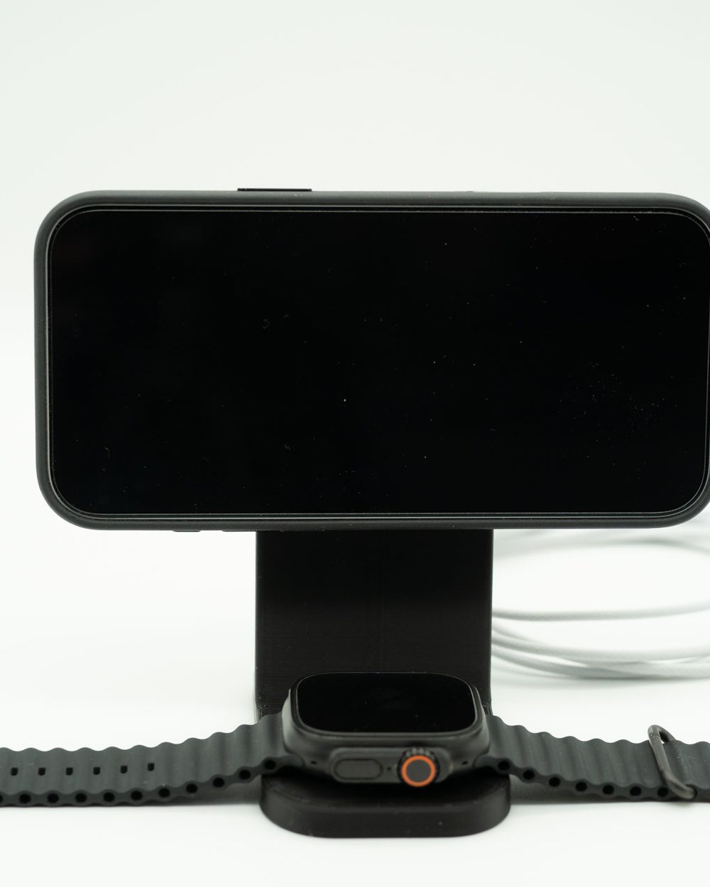 Suporte preto que carrega o iPhone na horizontal e o Apple Watch na base